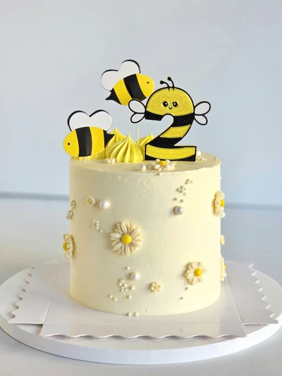 Bee-themed birthday cake with yellow daisies and bee toppers