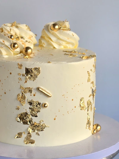 Elegant ivory cake with edible gold leaf and gold pearl details