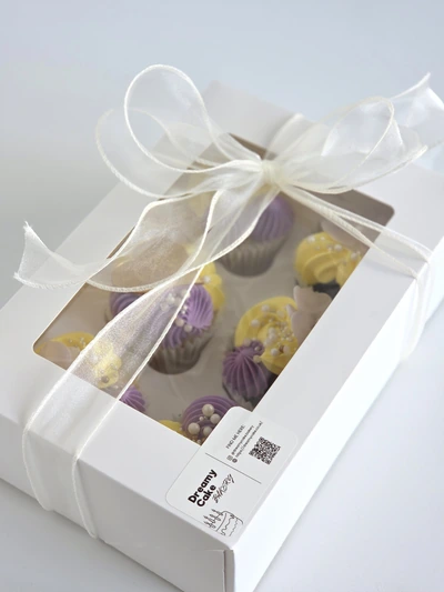 Assorted luxury cupcakes in a white gift box tied with a ribbon