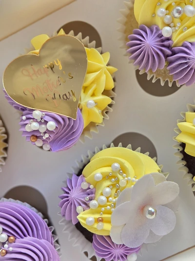 Close-up of Mother's Day cupcakes with purple and yellow swirls, pearls and a fondant flower
