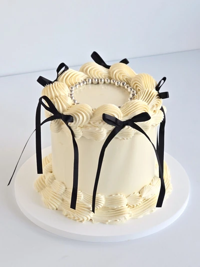 Vintage buttercream cake with black ribbon bows and pearl piping