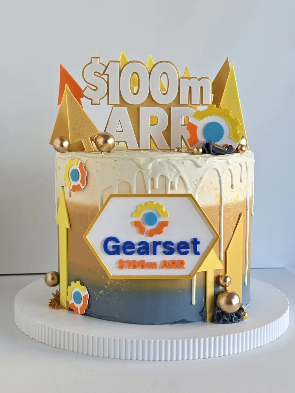 Gearset branded cake with gold decorations for a 100 million dollar ARR company milestone
