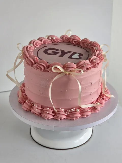 Pink Give Your Best launch cake with piped decoration and ribbon details