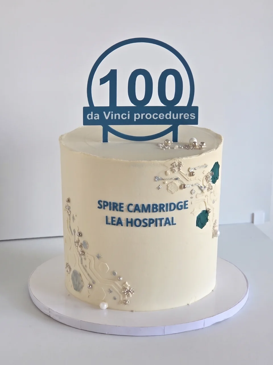 White and blue Spire Cambridge Lea Hospital cake celebrating 100 da Vinci procedures