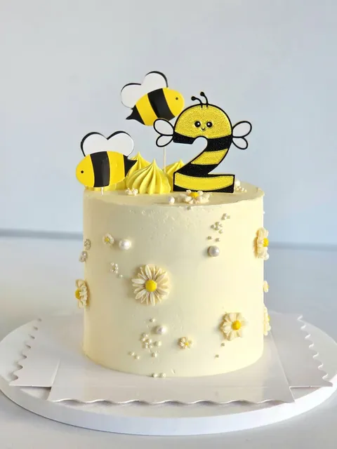 Bee-themed celebration cake with daisies and yellow buttercream swirls
