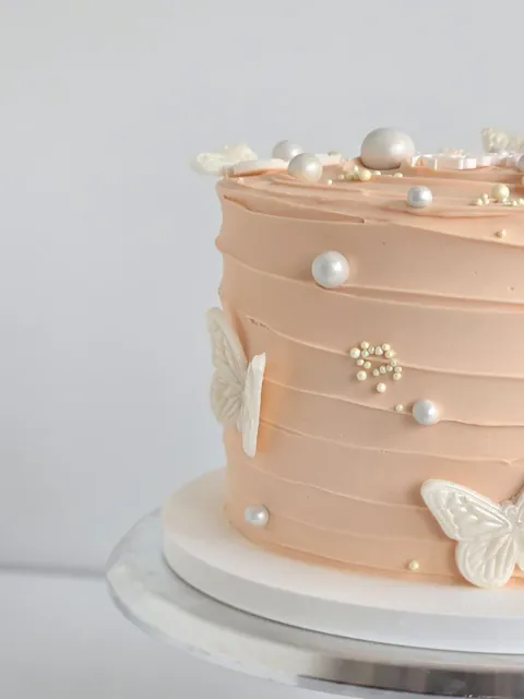 Blush birthday cake with butterflies and pearl decorations