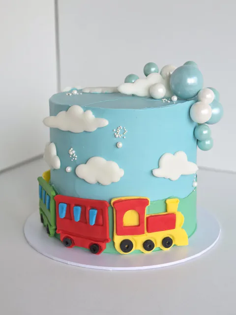Sky-blue birthday cake with a train, clouds and personalised name plaque