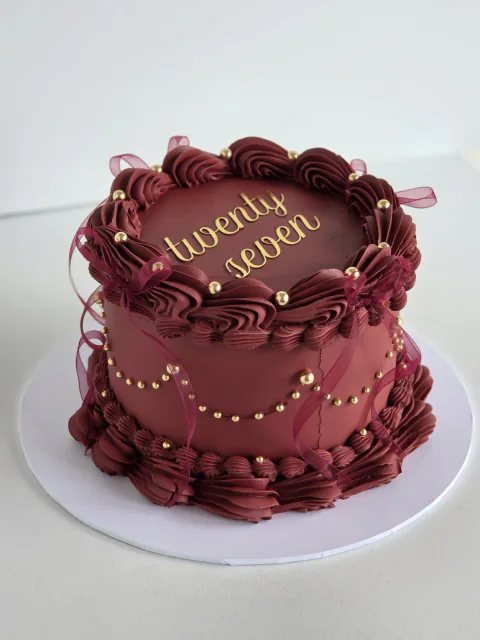 Burgundy twenty-seventh birthday cake with vintage piping, gold pearls and ribbon loops