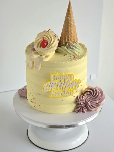 Pastel ice cream sundae birthday cake with waffle cone, cherry and piped swirls