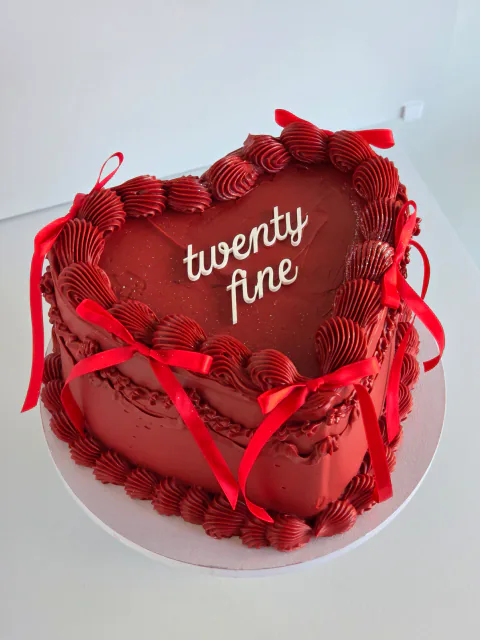 Red heart-shaped twenty-fifth birthday cake with vintage piping and ribbon bows