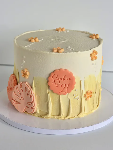 Cream 21st birthday cake for Sophie with peach tropical leaf decorations