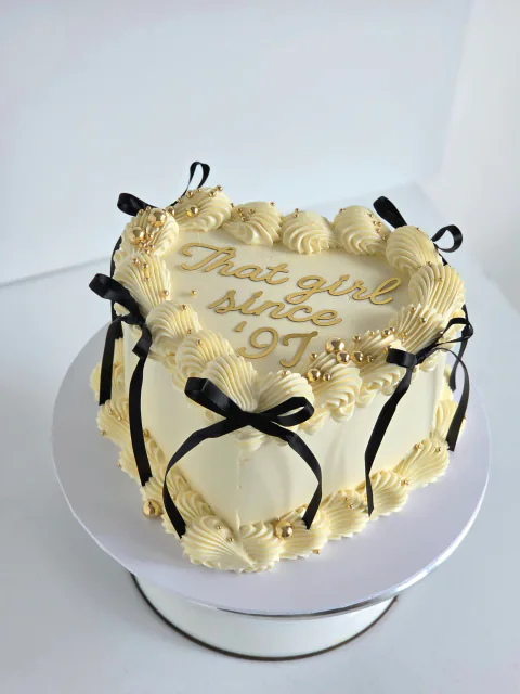 Ivory vintage-piped birthday cake with black bows and That Girl Since 91 message