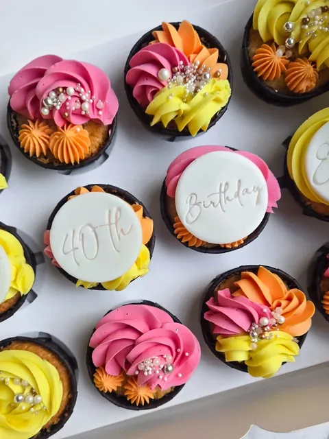 Colourful cupcakes with pink, yellow and orange frosting and 40th birthday toppers