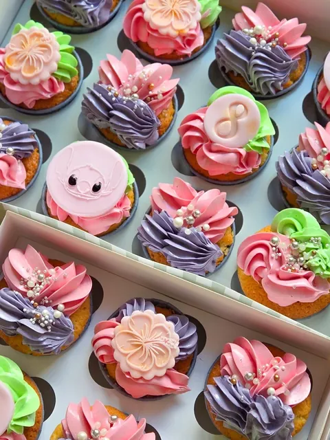Assorted cupcakes with pink and purple frosting, pearl sprinkles and custom toppers