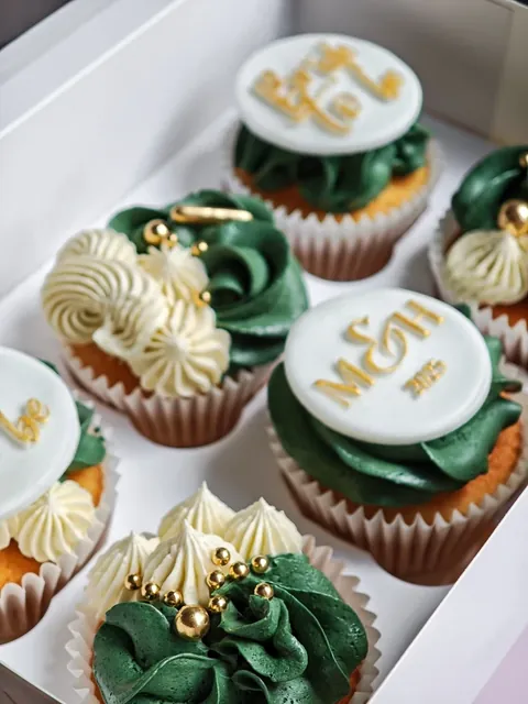 Cupcakes with dark green frosting, gold sprinkles and personalised monogram toppers