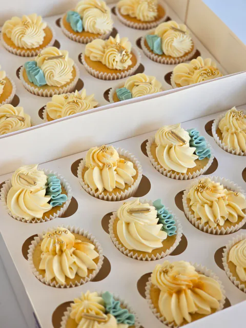Blue, yellow and cream cupcakes with classic buttercream swirls in gift boxes