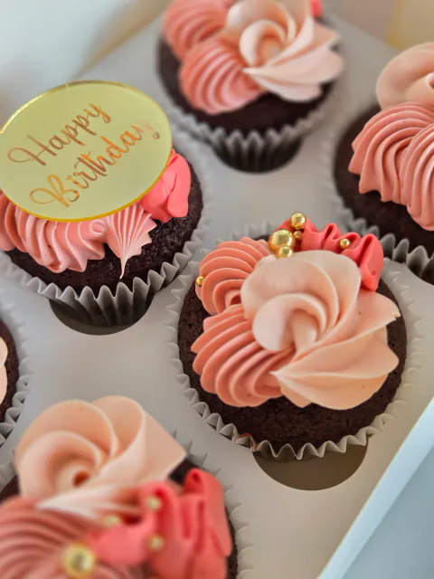 Pink birthday cupcakes with ribbon bows, cherries and Happy Birthday topper
