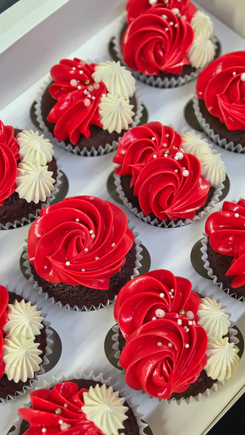 Red and cream cupcakes with generous buttercream swirls in a gift box