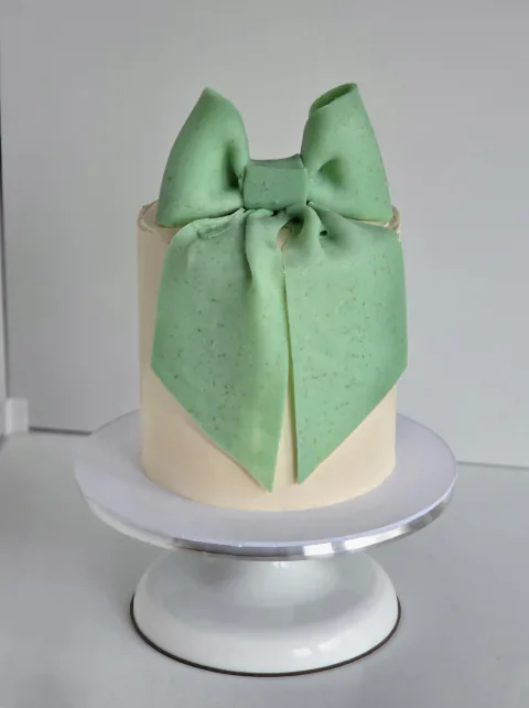 Ivory celebration cake finished with an oversized mint-green fondant bow