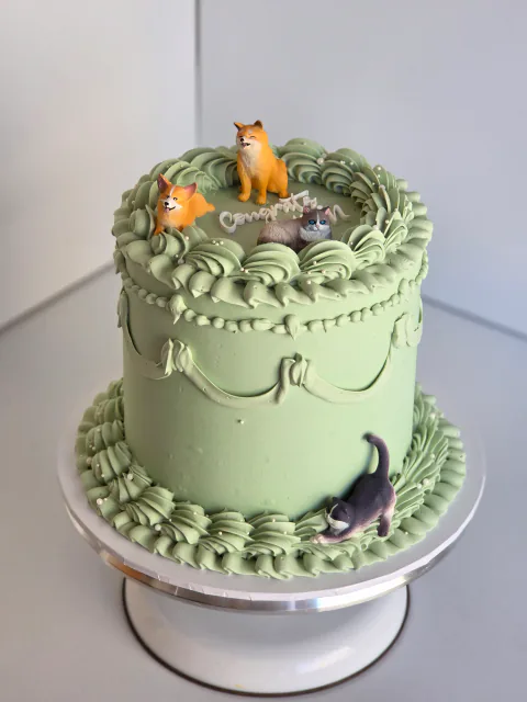 Sage green cat-themed cake with vintage piping and four cat figures