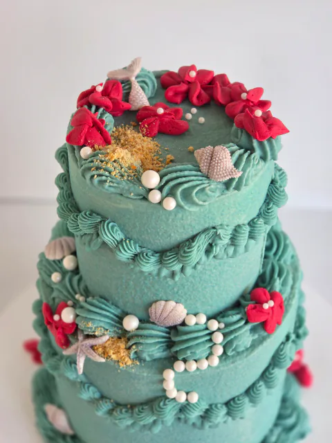 Two-tier mermaid cake with under-the-sea coral, shells and tail decorations
