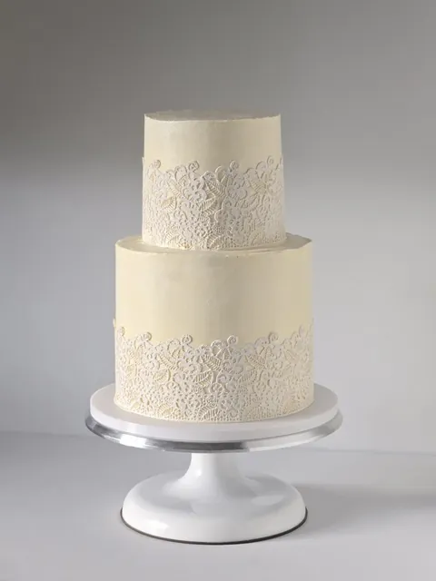 Ivory two-tier wedding cake with lace-textured buttercream