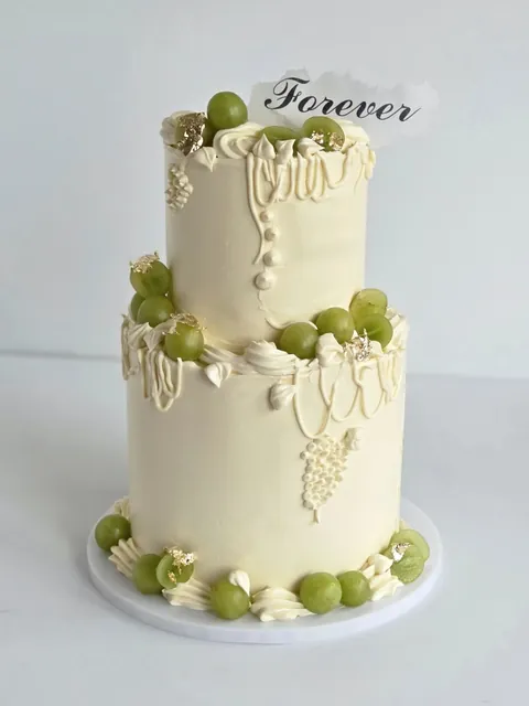 Two-tier wedding cake with ivory drips, green grapes and Forever topper