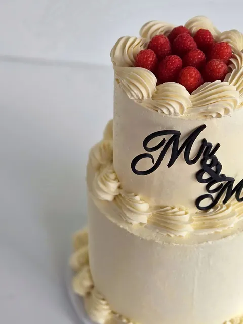 Wedding cake detail with raspberries and black Mr & Mrs topper