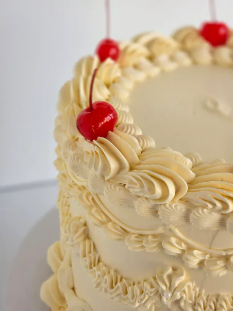 Cream heart-shaped wedding cake with vintage piping and cherry decorations