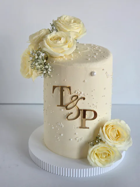 White wedding cake with fresh roses, baby's breath and gold T and P initials